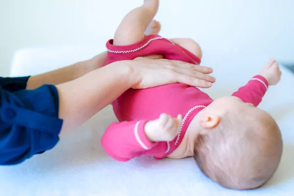 kinderosteopathie_14 Baby im pinken Strampler wird von Kinderosteopathin behandelt